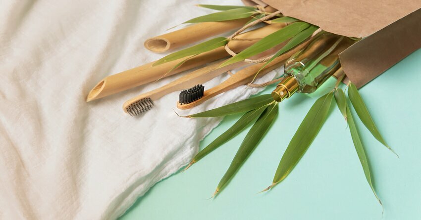 Bamboo tools spill out of a cardboard box which is laying against a white and green background.