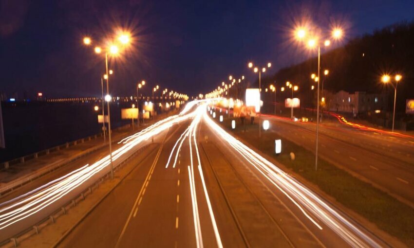 Cars buzz by on a European highway at night